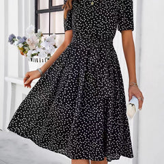 Black polka-dot midi dress with short sleeves and gathered waist, flowing skirt