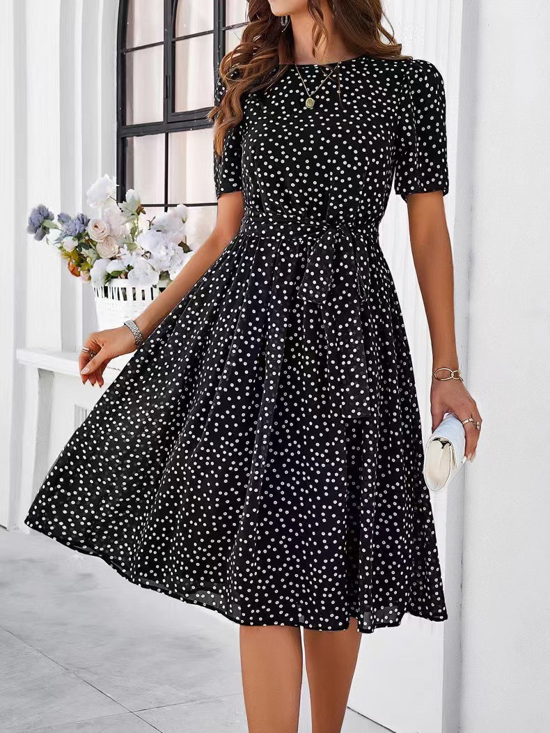 Black polka-dot midi dress with short sleeves and gathered waist, flowing skirt
