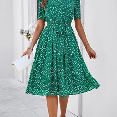 Green polka-dot midi dress with short sleeves, gathered waist, and full skirt