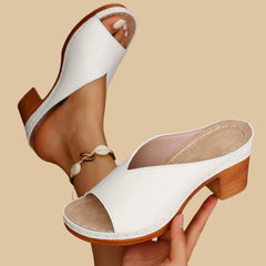 White heeled mule sandals with open toe, side strap detail, and wood-look block heel