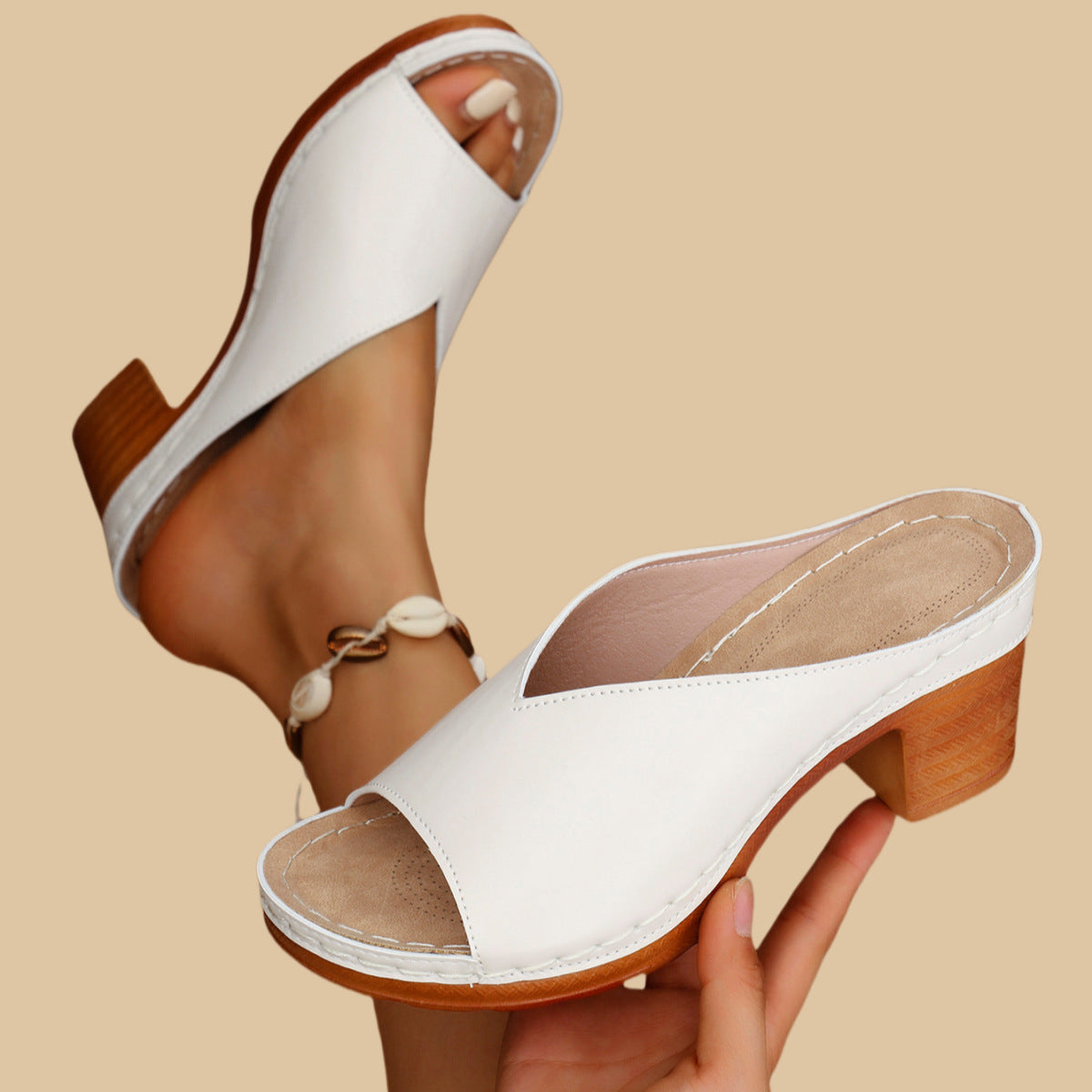 White heeled mule sandals with open toe, side strap detail, and wood-look block heel
