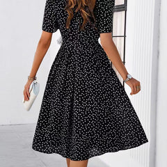 Black polka-dot midi dress with short sleeves, gathered waist, and full skirt