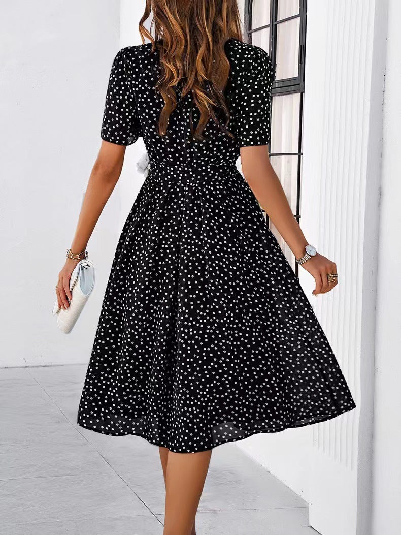 Black polka-dot midi dress with short sleeves, gathered waist, and full skirt
