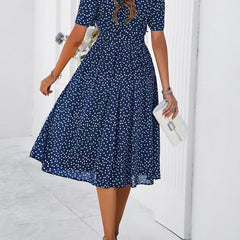 Navy polka-dot dress with short sleeves, tie waist, and flared midi skirt (side view)