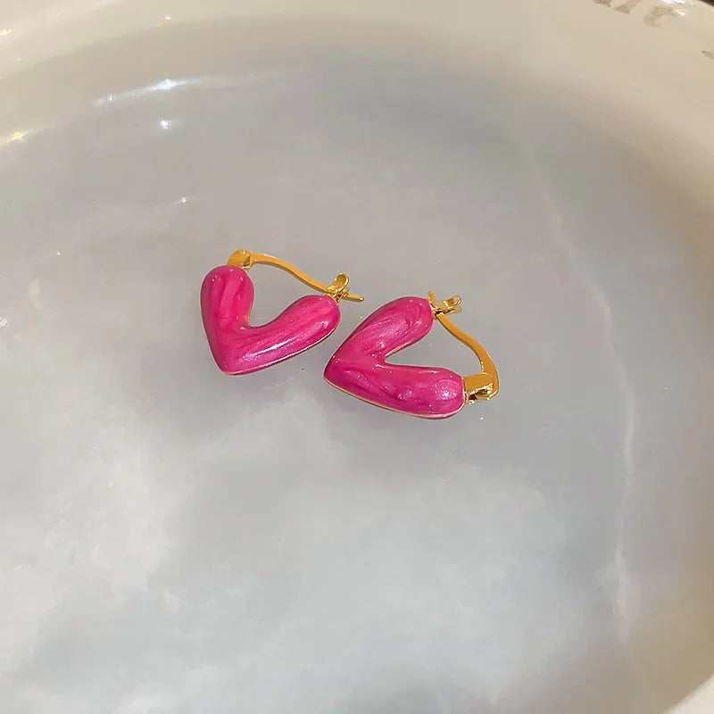 Hot pink heart hoop earrings with gold-tone hooks, glossy heart shape pair.