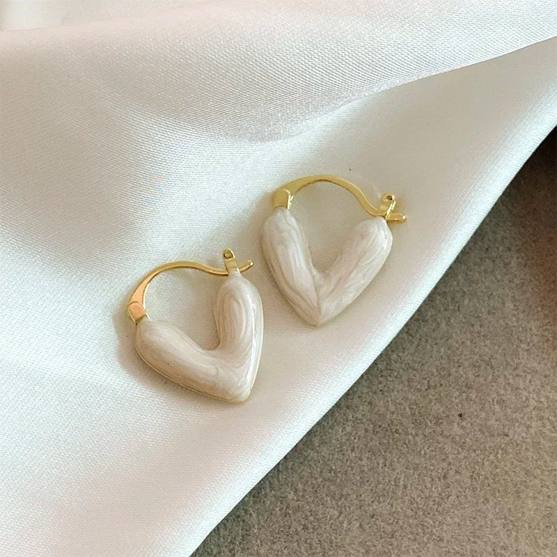 Gold heart hoop earrings with white resin heart details