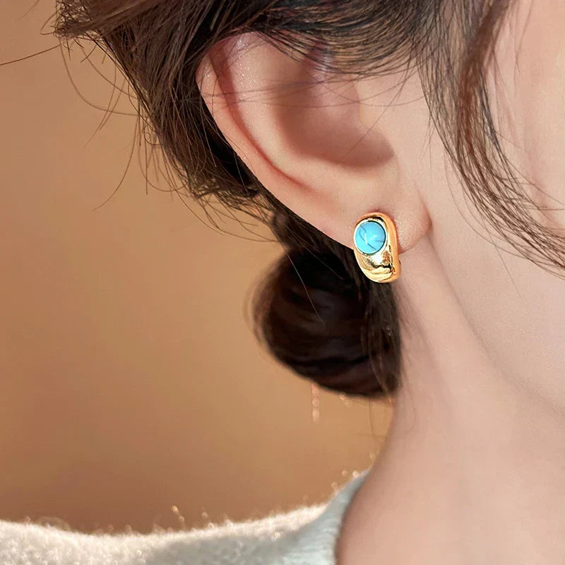 Gold hoop earrings with turquoise oval stone, worn on ear