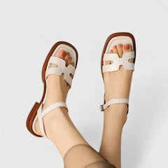 Brown flat sandals with white cross straps and adjustable buckle