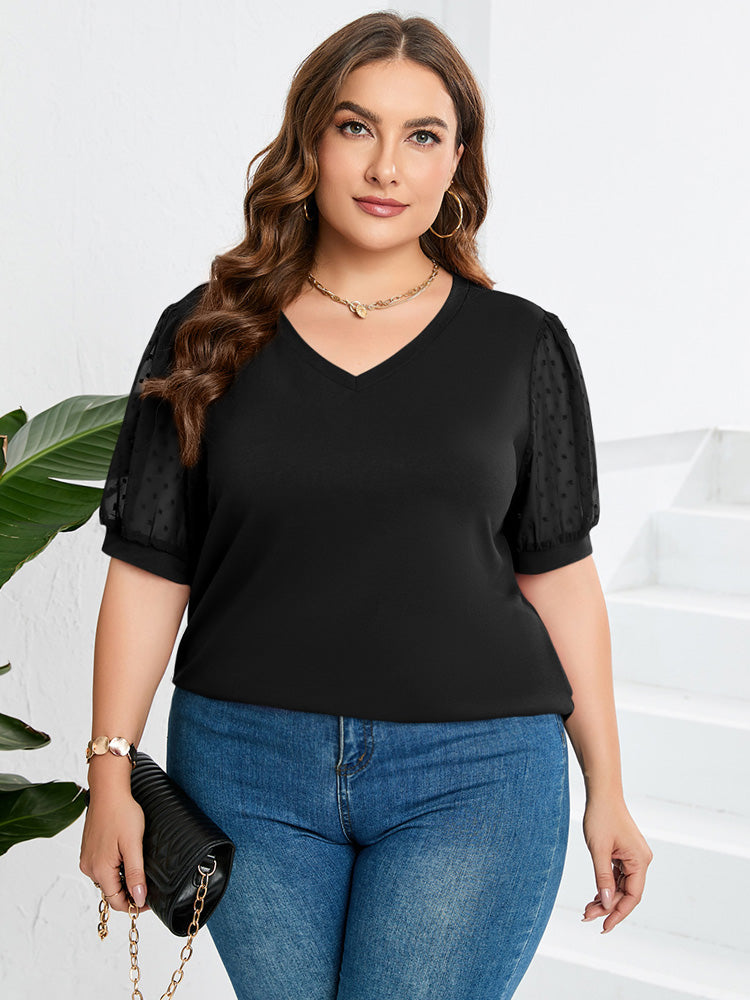 Black sheer-sleeve V-neck top with short puff sleeves, worn with jeans.