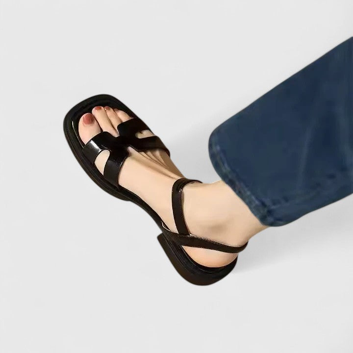 Black flat sandals with wide straps and buckle detail