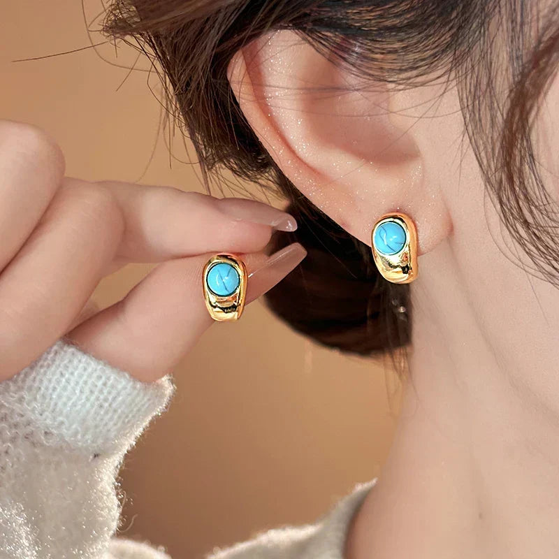 Turquoise cabochon gold hoop earrings on ear with short hairstyle