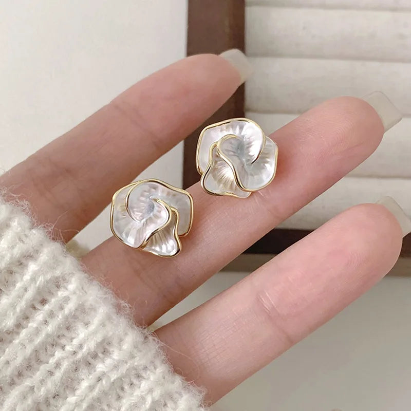 Pearl flower stud earrings in hand, gold-tone frames with white petal centers