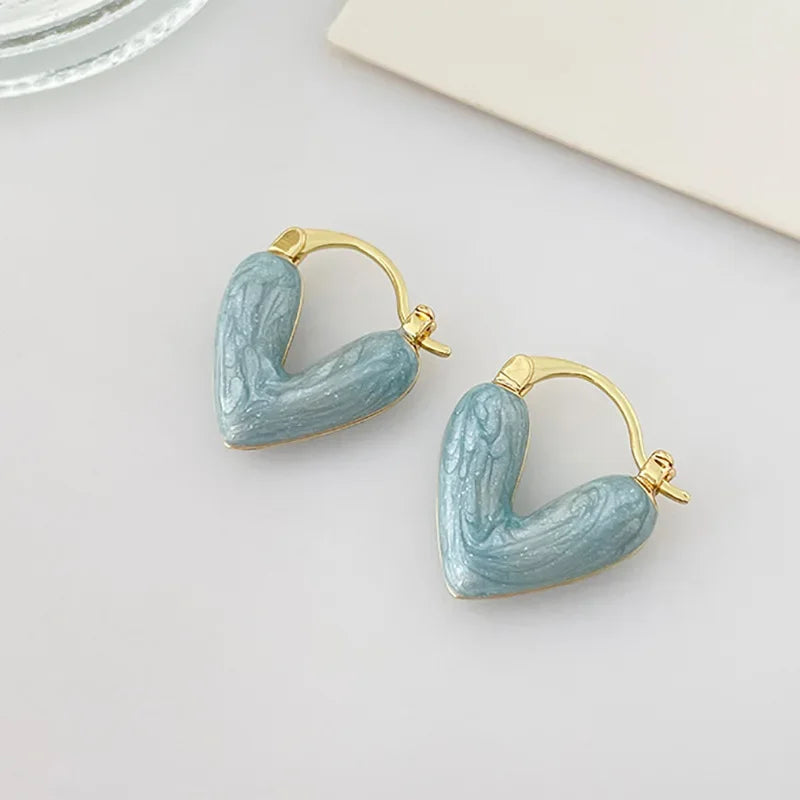 Light blue heart hoop earrings with gold-tone hooks, glossy molded heart shape.