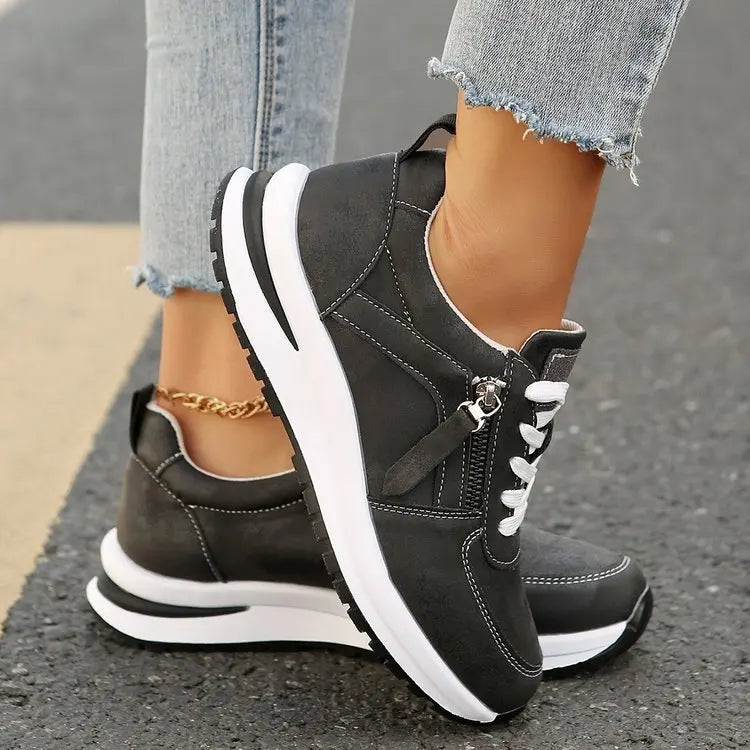 Black zip-up comfort sneakers with white laces, front zipper, and bold white sole