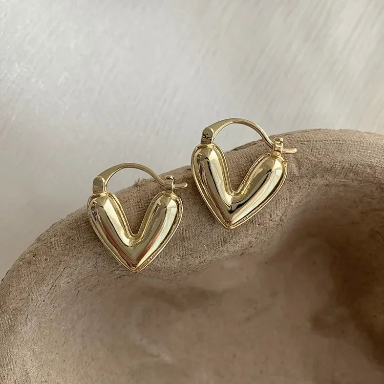 Gold heart hoop earrings with gold-tone wire, smooth heart front detail.
