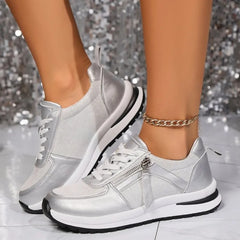 Silver metallic zip-up comfort sneakers with white laces, front zipper, and thick sole