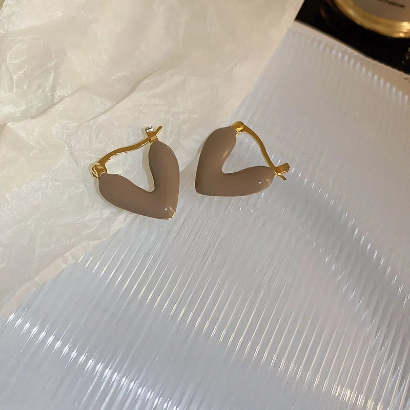 Taupe heart hoop earrings with gold-tone hooks, glossy heart shape pair.