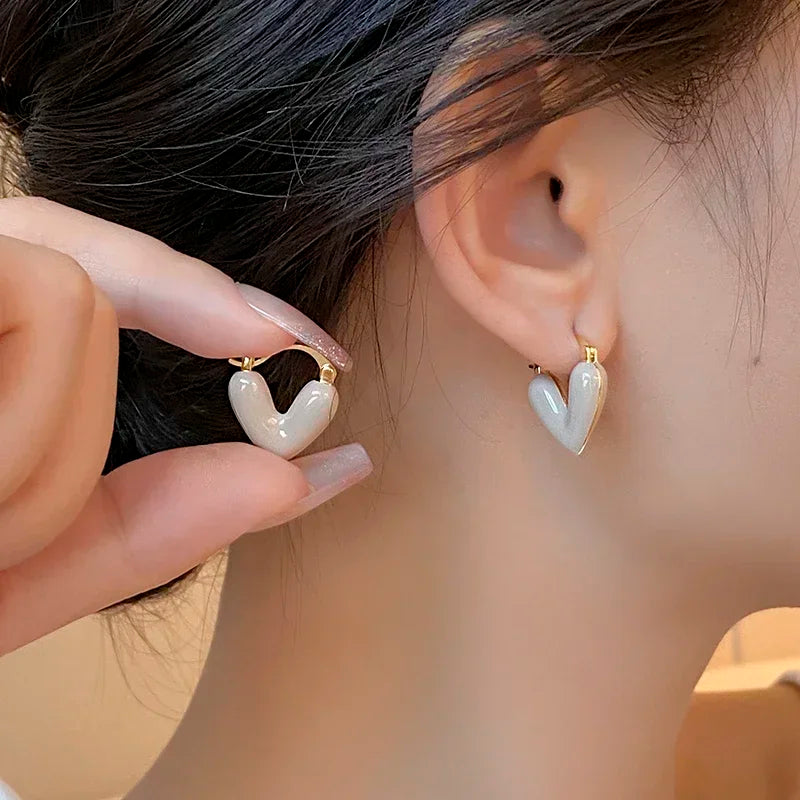 White heart hoop earrings with gold-tone hooks, glossy heart shape pair.