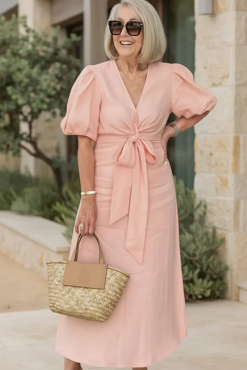 V-neck midi dress in soft pink with puff sleeves and tied waist.