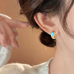 Turquoise stone gold hoop earrings close-up, on ear