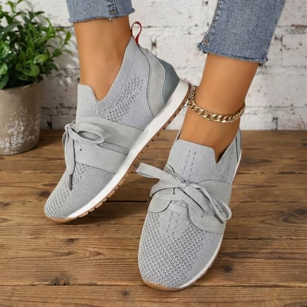 Light gray lace-up comfort sneakers with knit texture and flexible gum-style sole.