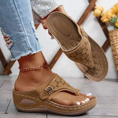 Brown Jean sandals with perforated detailing and adjustable buckle on a flat sole.