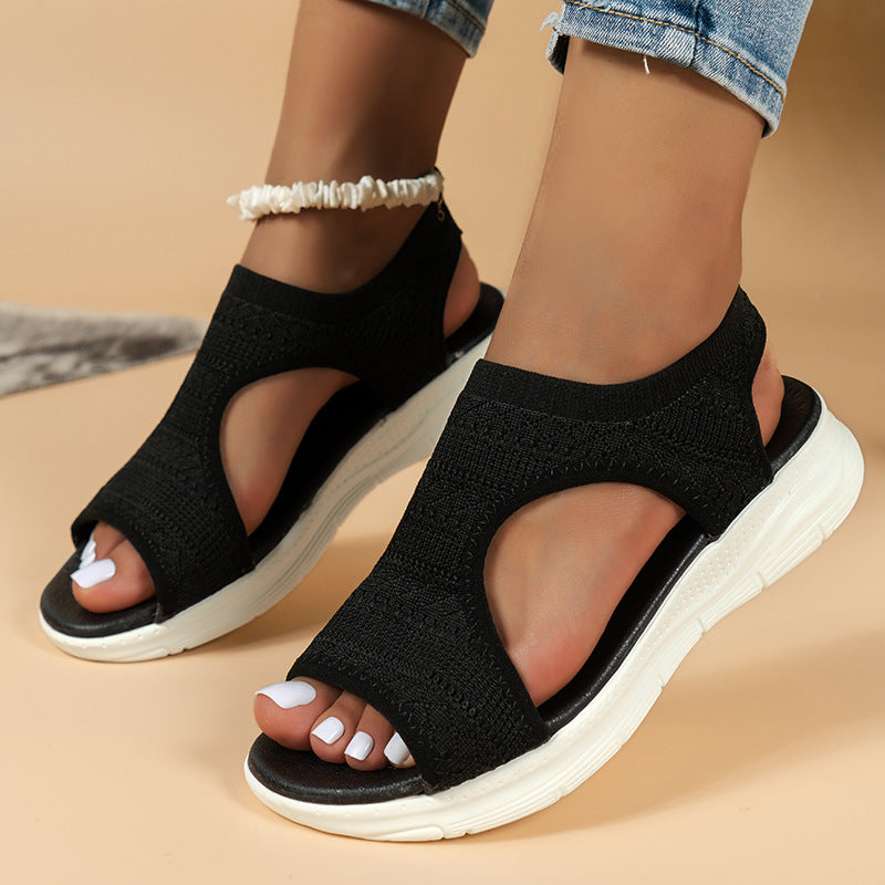 Black knit sandals with toe-out cutout and white sole, cross strap design