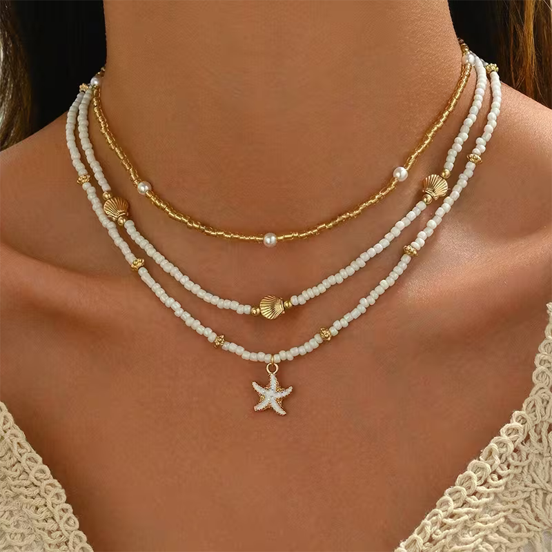 Layered beaded necklace set with white strands and gold accents, starfish pendant