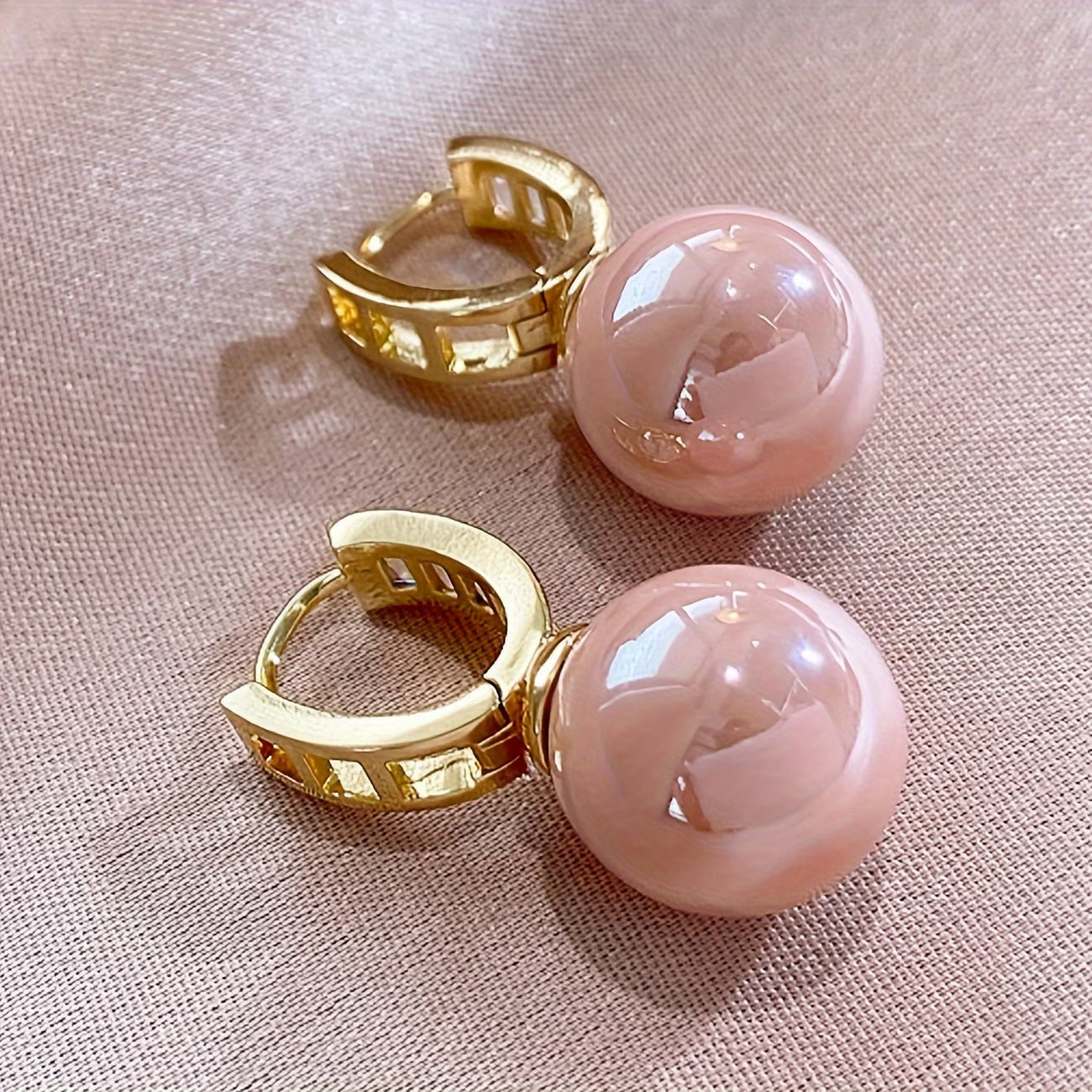 Gold hinged hoop earrings with pink spherical pearl drops and faceted stone trim.