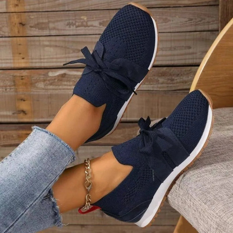 Navy comfort sneakers with lace-up bow detail and textured knit upper.