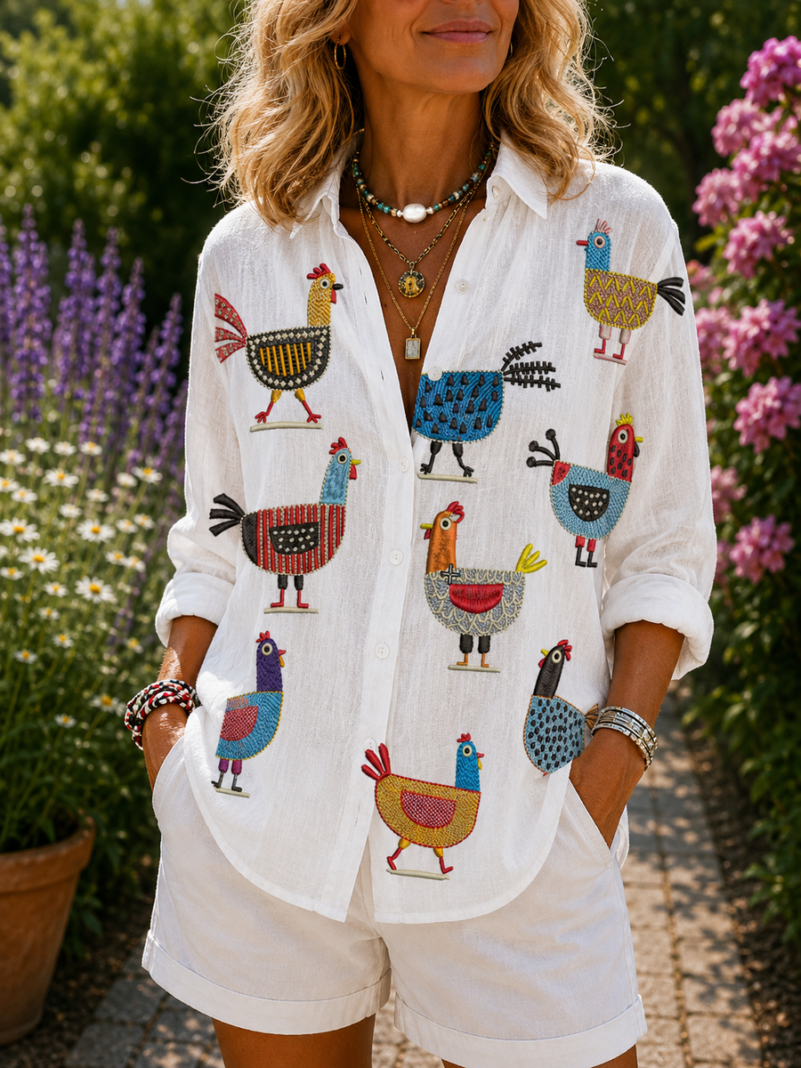 Ingrid hen print blouse in white with colorful rooster and bird pattern, button front.