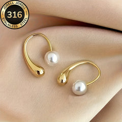 Gold-tone arc hoop pearl earrings, two earrings shown on light fabric