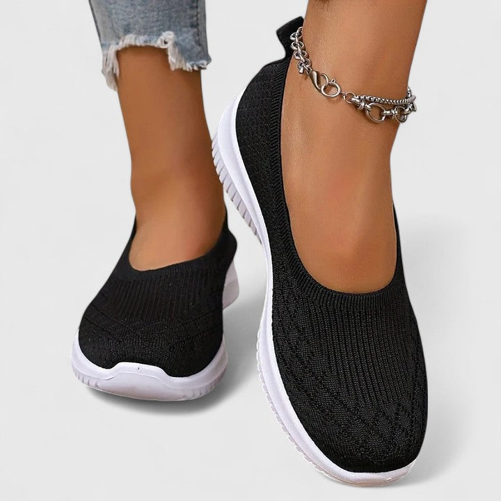 Black knit slip-on sneakers with white sole and ankle chain detail