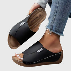 Black wedge sandals with wide strap and open toe, stitched trim and textured sole