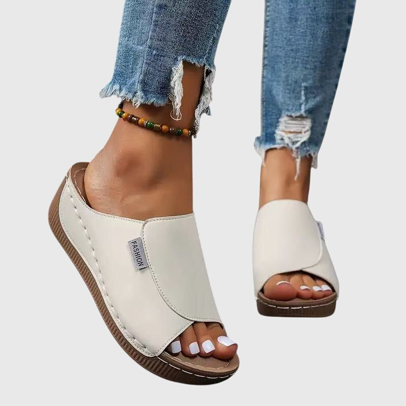 White wedge sandals with wide side strap and open toe, stitched trim and textured sole