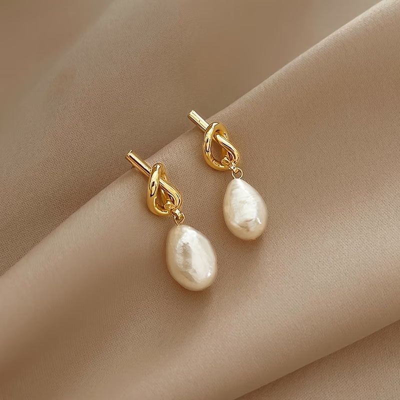 Gold hoop earrings with knotted links and white teardrop pearl drops