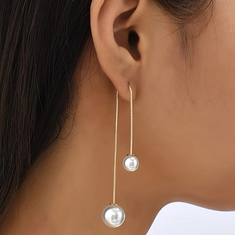 Long gold-tone drop earrings featuring two round white pearls