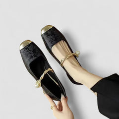 Orthopedic shoes, pair view, black textured flats with gold toe caps and gold bow straps