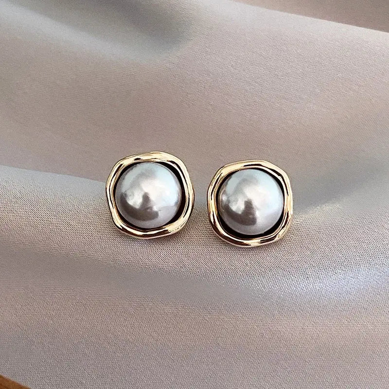 Round stud earrings with gold-tone bezel and pearl-like center