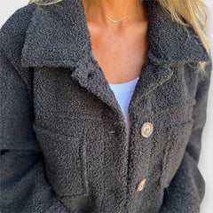 Close-up of black sherpa-style coat with button placket and round metal-look buttons.