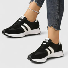 Black comfort sneakers with white side stripes and lace-up front, chunky sole