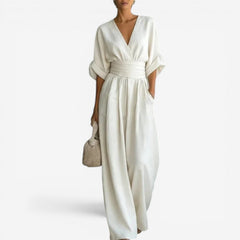 Cream V-neck jumpsuit with gathered waist and wide-leg drape.