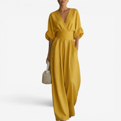 Mustard yellow V-neck jumpsuit with cinched waist and flowing wide legs.