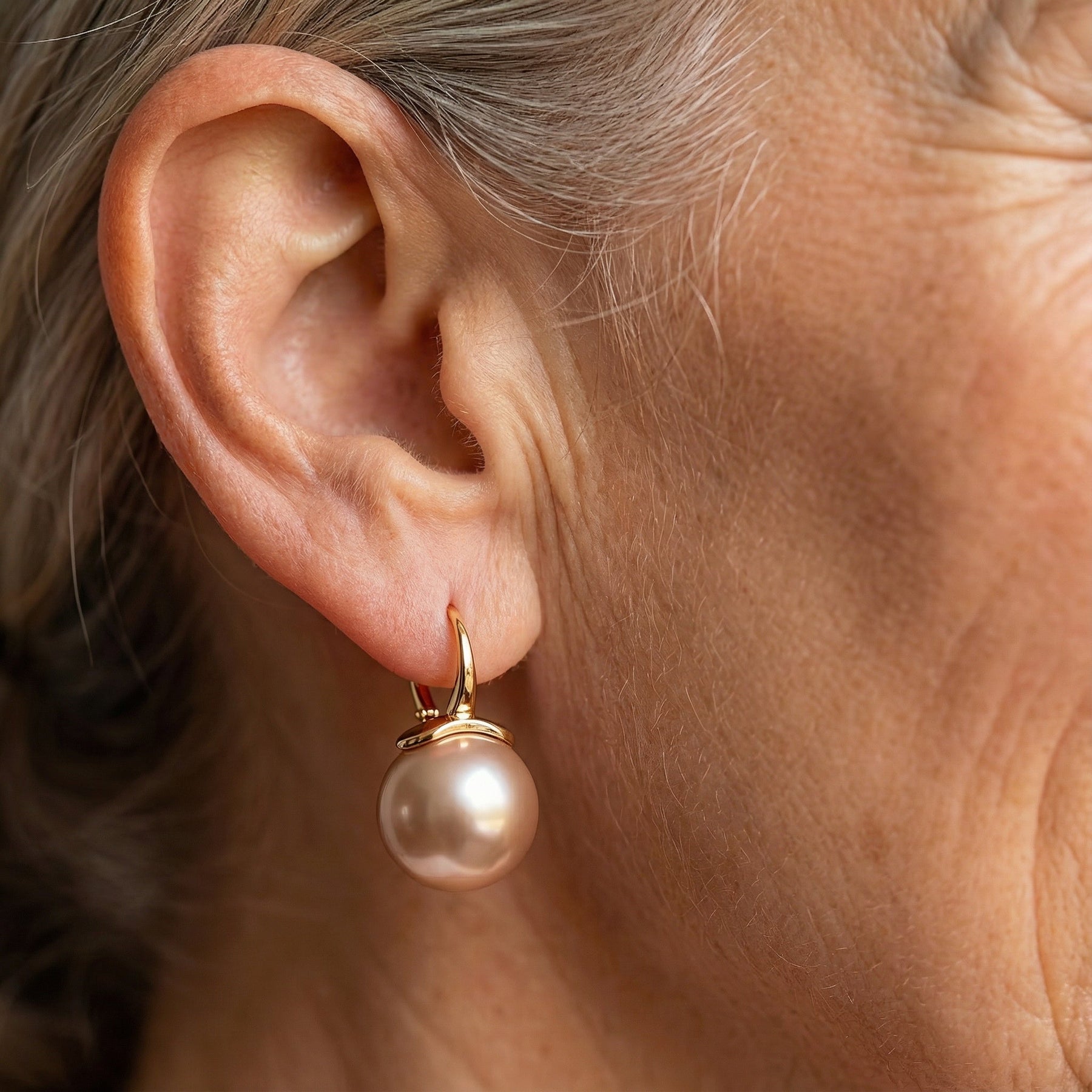 Gold hoop pearl earrings on model ear, large round white pearl drop
