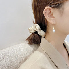 Gold-tone pearl dangle earrings on model with long white pearl drops