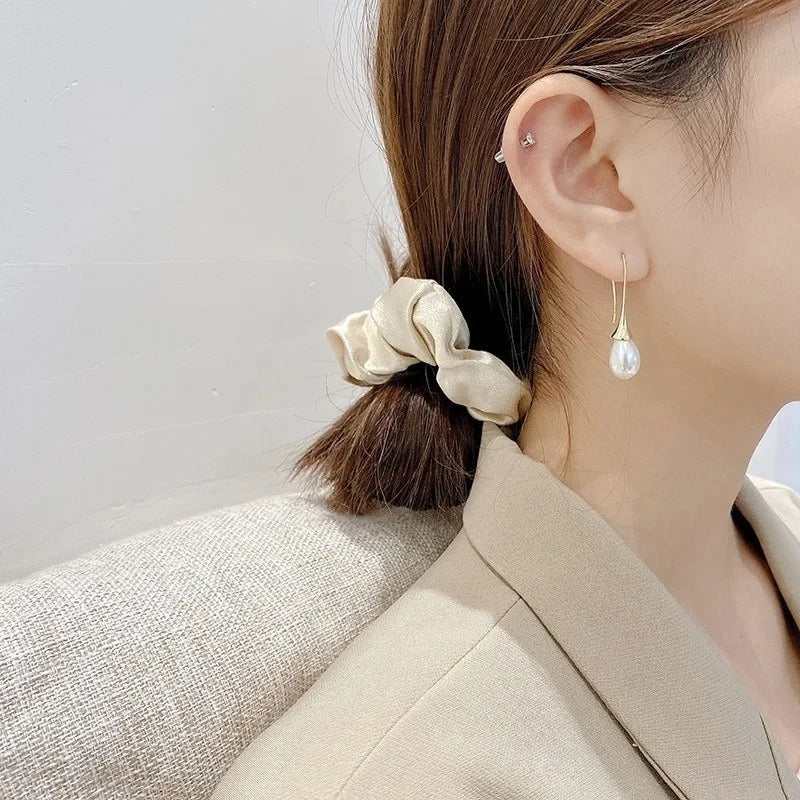 Gold-tone pearl dangle earrings on model with long white pearl drops