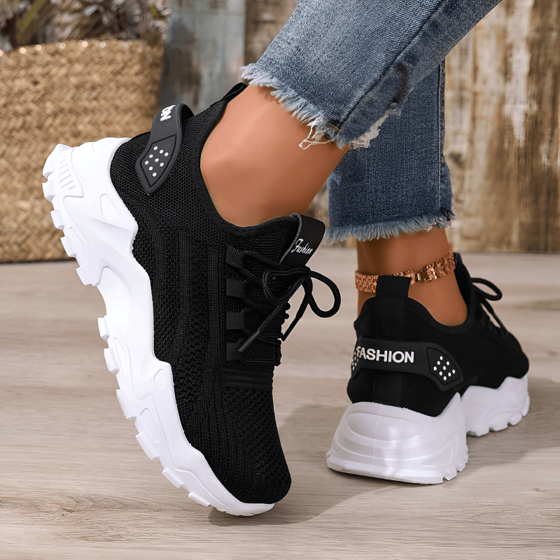 Black lace-up sneakers with breathable knit upper and white tread sole