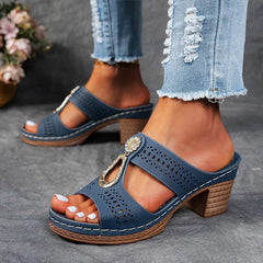Blue perforated slide sandals with rhinestone charm and chunky mid-height heel