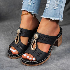 Black perforated slide sandals with decorative charm straps and block heel