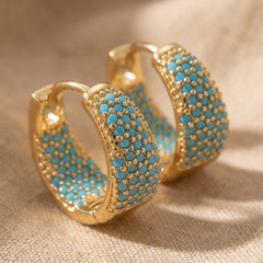 Gold-tone hoop earrings with turquoise beaded lattice design, textured front